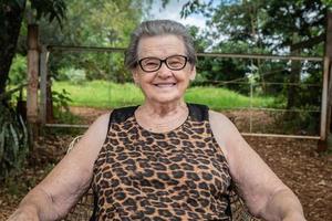 Senior gelukkige oude boer vrouw met bril glimlachen en kijken naar camera foto