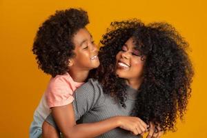 portret van jonge Afro-Amerikaanse moeder met peuter zoon. gele achtergrond. Braziliaanse familie. foto