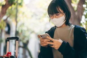 jonge volwassen aziatische vrouw die reist, draagt een gezichtsmasker om het coronavirus of covid-19 te beschermen. foto