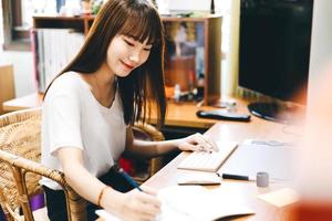 Aziatische tienervrouw blijft thuis internet gebruiken voor werk en studie foto