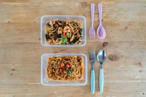 spaghetti varkensvlees tomatensaus met pittige gemengde zeevruchten in plastic doos en lepel voor levering op tafel foto