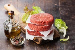 een stapel van rauwe rundvlees hamburgers op een snijplank foto