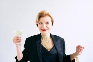 volwassen stijlvolle elegante vrouw in smoking met een glas mousserende wijn. feest, feest, anti-leeftijd concept foto