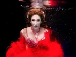 portret van de mooie vrouw onder water in rode jurk op zwarte achtergrond foto