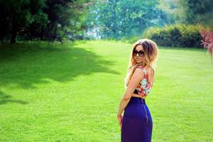 stijlvolle coole slim fit vrouw in zonnebril op de achtergrond van gras. mode, stijl, trends, reisconcept foto