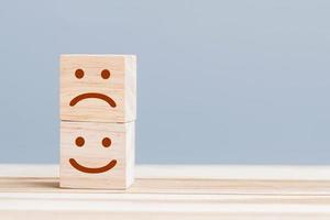 emotie gezicht symbool op houten kubus blokken. servicebeoordeling, rangschikking, klantbeoordeling, tevredenheid en feedbackconcept foto