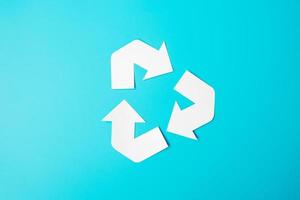 papier recycle logo knipsel op blauwe achtergrond. milieubescherming, afvalvrij, herbruikbaar, zeg geen plastic, wereldmilieudag, ecologiedag en aardedagconcept foto