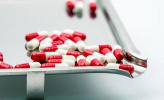 rood-witte antibiotische capsulepillen op roestvrijstalen medicijnbakje. resistentie tegen antibiotica. voorgeschreven medicijnen. farmaceutische industrie. foto
