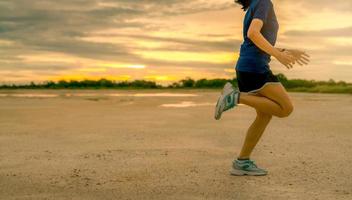 aziatische vrouw runner cardio-oefening in de ochtend. zijaanzicht van vrouw benen springen. fit en sterke vrouw outdoor workout voor gezond leven. lopende beweging van de loper. fit meisje training voor marathon. foto