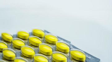 macro shot detail van gele ovale tablet pillen in blisterverpakkingen op witte achtergrond met kopie ruimte. pijnstillend medicijn. geneesmiddel voor het verlichten van menstruatiekrampen bij vrouwenperiodes foto