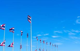 veel van thailand vlag zwaaien op de top van vlaggenmast tegen blauwe hemel. Thaise vlag werd naar de top van de vlaggenmast getrokken. rode, blauwe en witte kleur rechthoek stof. nationale vlag van het koninkrijk thailand. foto