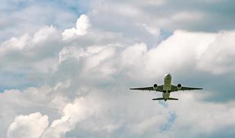 commerciële luchtvaartmaatschappij vliegen op blauwe lucht en witte pluizige wolken. onder het oog van vliegtuig vliegen. passagiersvliegtuig na het opstijgen of naar de landingsvlucht. vakantiereizen naar het buitenland. luchttransport. foto