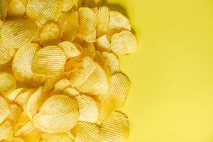 krokante aardappel bovenaanzicht, chips snack op gele achtergrond foto