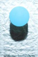 ronde blauwe object op abstracte blauwe achtergrond. minimalistisch plat lag enkel object met schaduw. foto