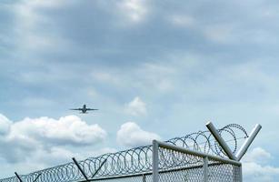 vliegtuig vliegen op blauwe lucht en witte wolken boven metalen hek. luchtvaart zaken. commercieel vliegtuig. luchttransport. hek voor veiligheid en beveiliging. luchtvaart zaken. Met het vliegtuig reizen. foto