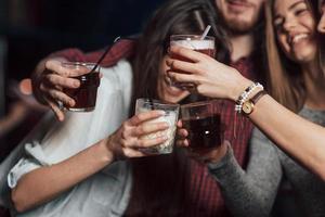 feest met alcohol. groep jonge vrienden die glimlachen en een toast uitbrengen in de nachtclub foto