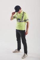 gezicht achter de hoed verbergen. politieagent in groen uniform staat tegen een witte achtergrond in de studio foto