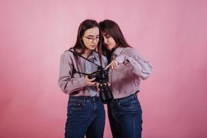 meisjes beheersen de kunst van fotografie. twee zussen tweeling staan en poseren in de studio met witte achtergrond foto