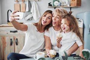 toont tongen. moeder, grootmoeder en dochter hebben het naar hun zin in de keuken foto