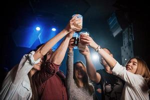 drinkt op. groep jonge vrienden die glimlachen en een toast uitbrengen in de nachtclub foto