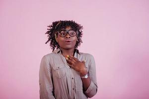 toont schokkende uitdrukking. aantrekkelijke afro-amerikaanse vrouw in vrijetijdskleding op roze achtergrond in de studio foto