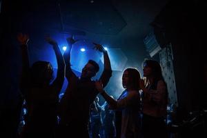 gelukkige jeugd. groep mensen die genieten van dansen in de nachtclub met prachtige verlichting foto