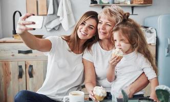 selfie op smartphone. moeder, grootmoeder en dochter hebben het naar hun zin in de keuken foto