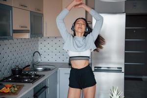 dansen op de muziek. meisje in de moderne keuken thuis in haar weekend in de ochtendtijd foto