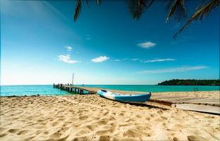 prachtig uitzicht tropisch paradijs strand van resort. kokospalm, houten brug en kajak in het resort op zonnige dag. zomervakantie concept. zomerse sferen. gouden zandstrand van resort met blauwe lucht. foto