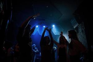 die muziek is zo aanstekelijk. groep mensen die genieten van dansen in de nachtclub met prachtige verlichting foto