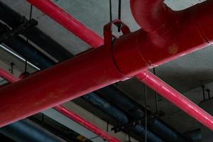 sprinklerinstallatie met rode pijpen die aan het plafond in het gebouw hangen. brandbestrijding. brandbeveiliging en detector. hoofdtoevoerwaterleidingen in het brandblussysteem in het ziekenhuis. foto