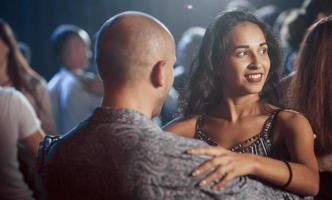 veel mensen in de buurt. paar dansen 's nachts in de club. genieten van muziek en elkaar foto