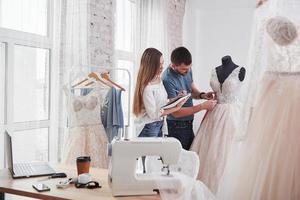 aantekeningen in het leerboek. het proces van het passen van de jurk in de studio van handgemaakte kleding foto