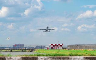 passagiersvliegtuig vertrekt op de luchthaven met prachtige blauwe lucht en witte pluizige wolken. het verlaten van de vlucht boven het prikkeldraad van de luchthaven. vrijheidsconcept. witte vogels vliegen onder vliegtuig op de luchthaven. foto