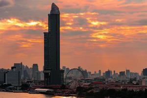 stadsgezicht van modern gebouw in de buurt van de rivier in de ochtend met oranje zonsopganghemel en wolken in bangkok in thailand. moderne architectuur kantoorgebouw stadsgezicht. foto