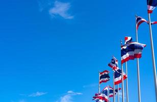 veel van thailand vlag zwaaien op de top van vlaggenmast tegen blauwe hemel. Thaise vlag werd naar de top van de vlaggenmast getrokken. rode, blauwe en witte kleur rechthoek stof. nationale vlag van het koninkrijk thailand. foto