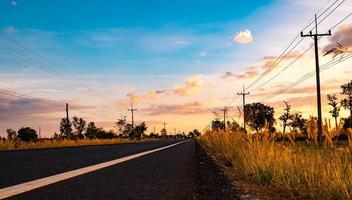 asfaltweg met elektrische paal en weiden langs de weg. platteland in thailand foto