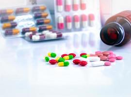 kleurrijke tabletten en capsulepillen op onscherpe achtergrond van medicijnfles en antibiotische capsulepillen. farmaceutische industrie. achtergrond voor inhoud van drugsgebruik bij zwangere vrouwen en ouderen. foto