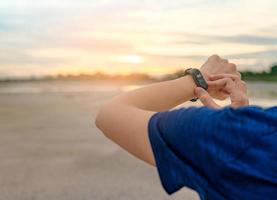 jonge aziatische vrouw die 's ochtends slimme band aanraakt na het hardlopen. draagbare computer. hartslagmeter armband. fitness apparaat. activiteits- of fitnesstracker. smartwatch aangesloten apparaat. polsbandje foto