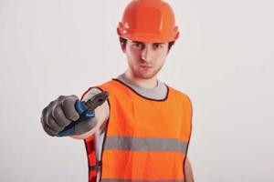 metalen instrument klaar voor het werk. man in oranje gekleurd uniform staat tegen een witte achtergrond in de studio foto