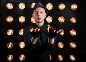 controle van het verbrandingsproces. professionele illusionist in zwarte hoed, shirt en handschoenen spelen met vuur foto