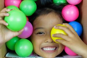 een meisje dat breed lacht en speelt in de kleurrijke bal foto