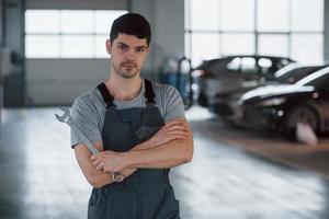 onze beste medewerker. portret van serieuze werknemer in uniform die in zijn werkplaats staat met een moersleutel in de hand? foto