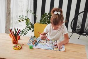 geconcentreerd aan het werk. schattig klein meisje op de kunstacademie tekent haar eerste schilderijen met potloden en stiften foto