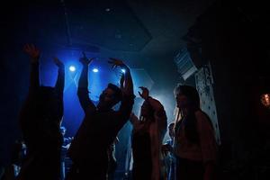 groep mensen die genieten van dansen in de nachtclub met prachtige verlichting foto