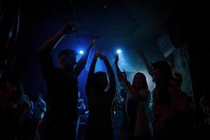 energiek publiek. groep mensen die genieten van dansen in de nachtclub met prachtige verlichting foto