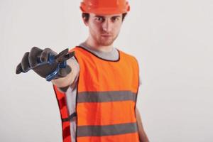 blauw gekleurd gereedschap. man in oranje gekleurd uniform staat tegen een witte achtergrond in de studio foto