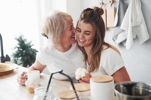 daglicht komt uit het raam. moeder en dochter hebben plezier in de keuken foto