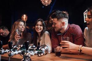 vriendelijk gesprek. mooie jongeren hebben feest samen met alcohol in de nachtclub foto