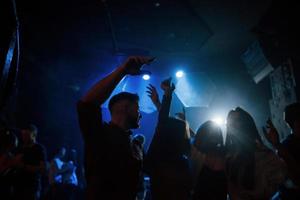 leuk feestje. groep mensen die genieten van dansen in de nachtclub met prachtige verlichting foto